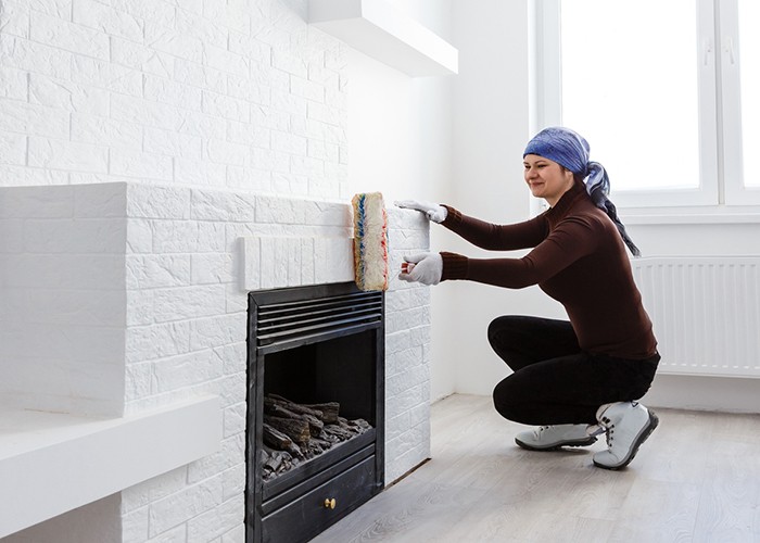 woman painting brick fireplace